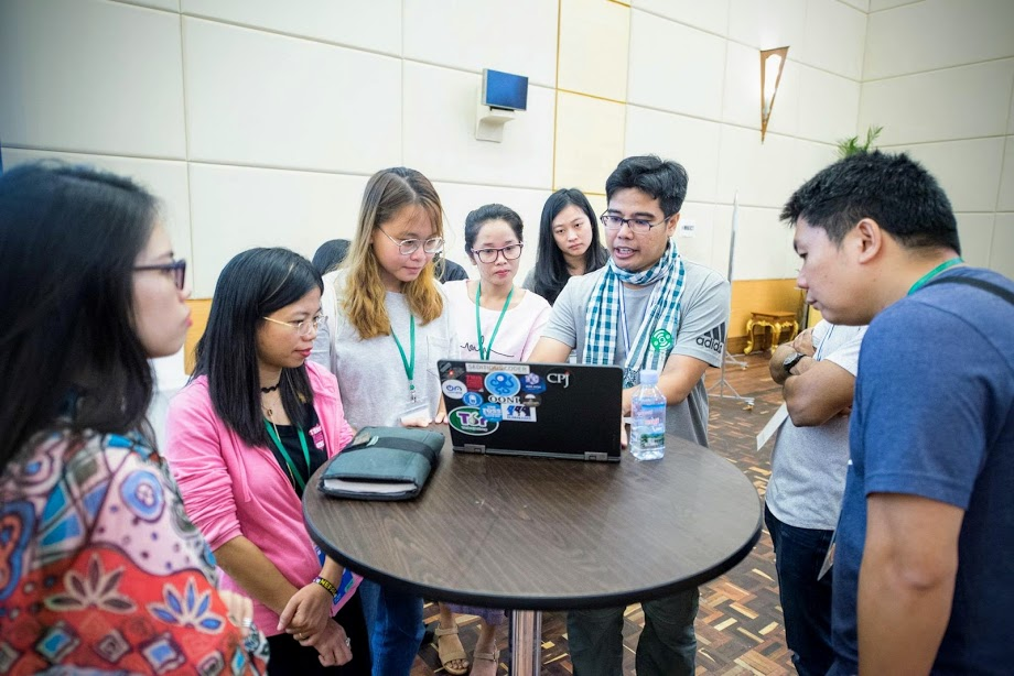 Several people gathered around a high table looking at a laptop.