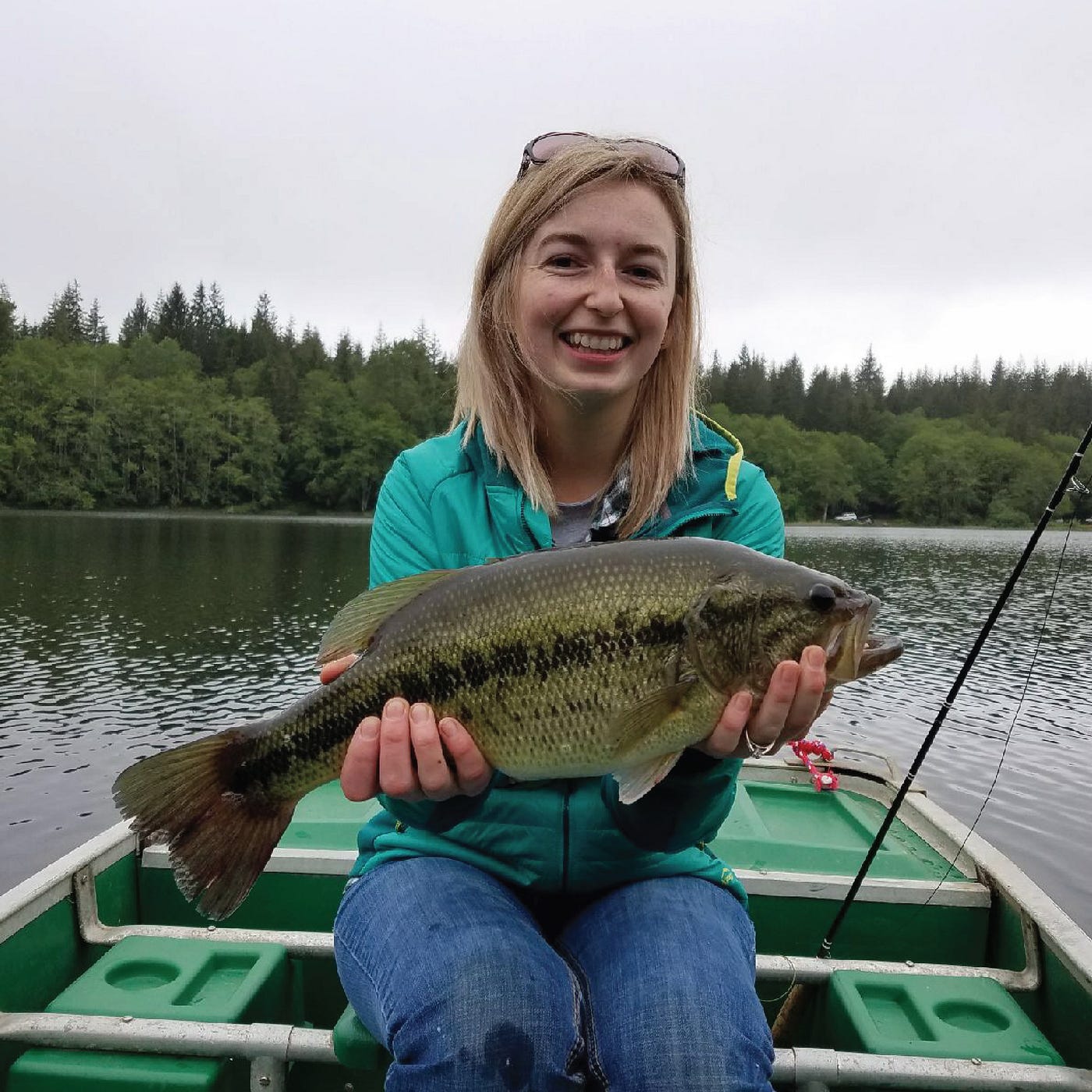 A woman holds a hefty bass she has just caught
