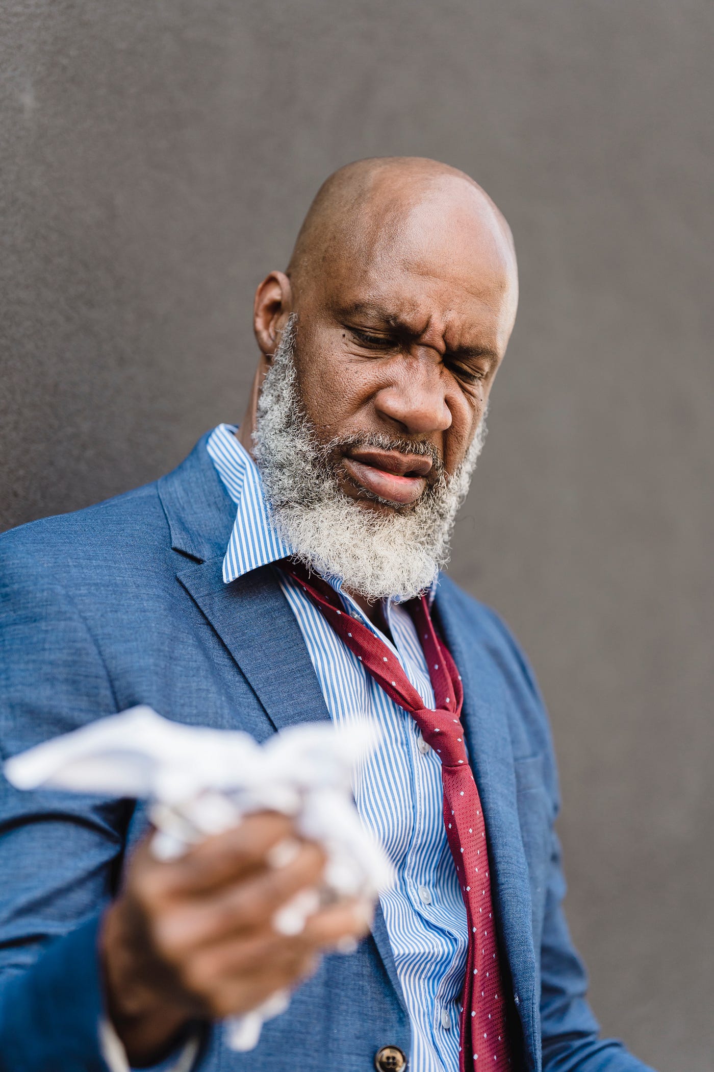 man in suit coat and loose tie crumpling paper
