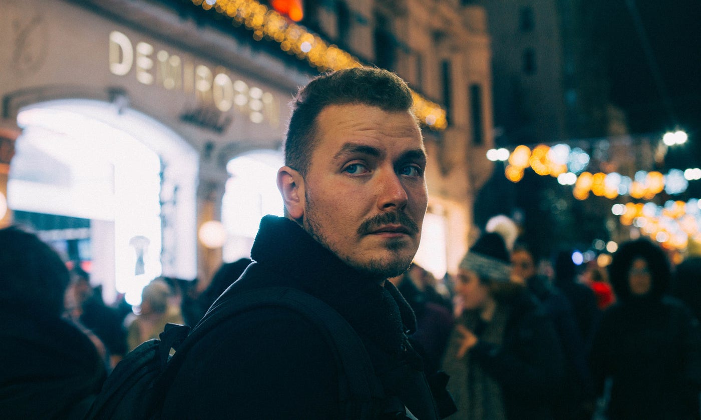 Man looking toward camera with nighttime street scene in background