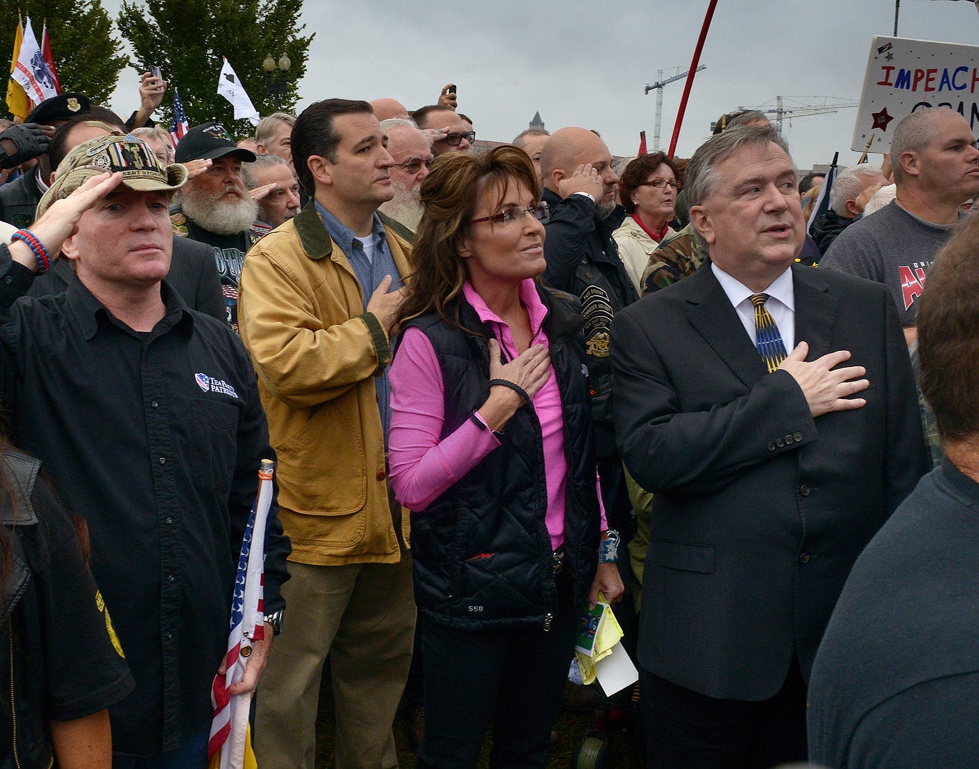 Former VP candidate Sarah Palin, Sen. Ted Cruz (R-TX), and others hold their hands over their hearts at a rally.