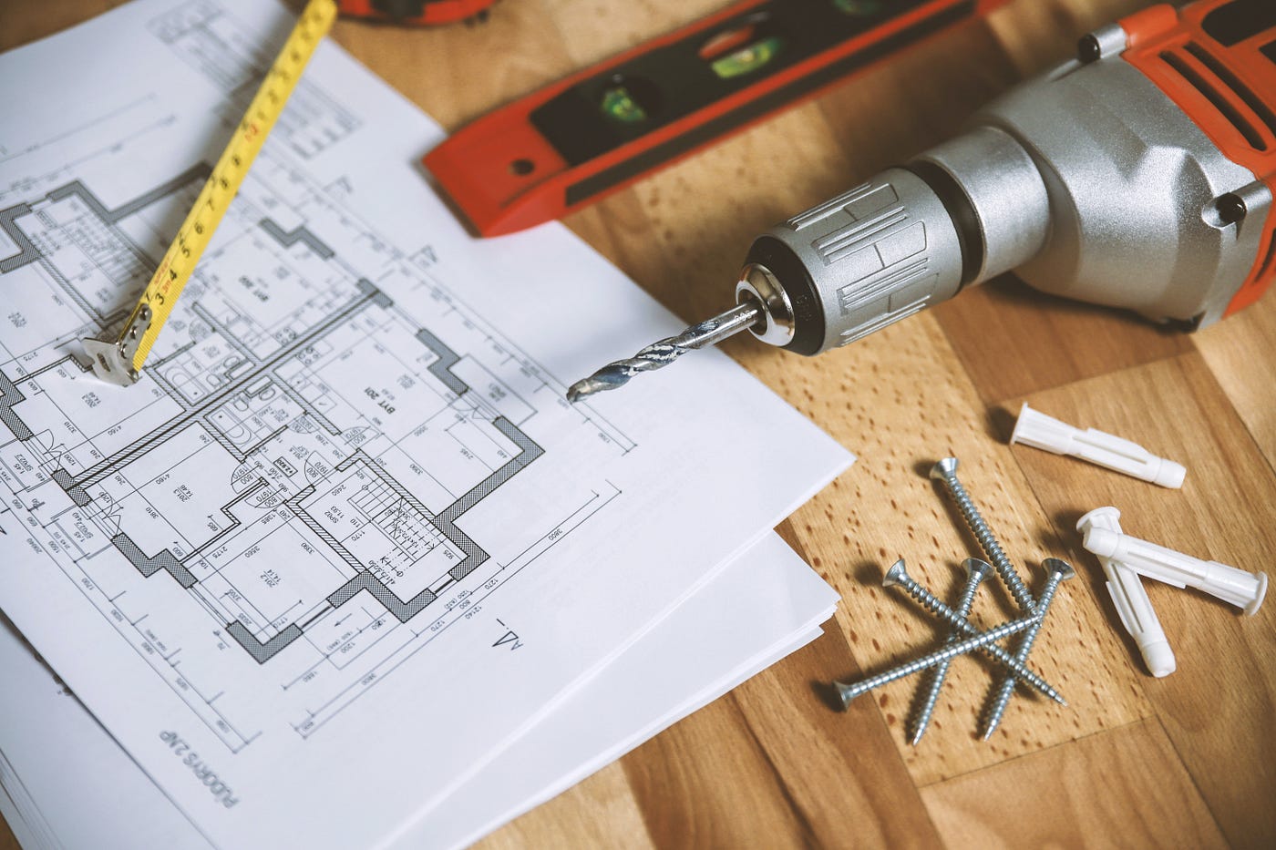 blueprint with drill, pencil, screws, measuring tape on top