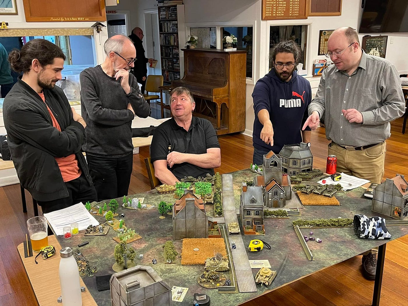 Image of a wargame setup on a table with gamers interacting.