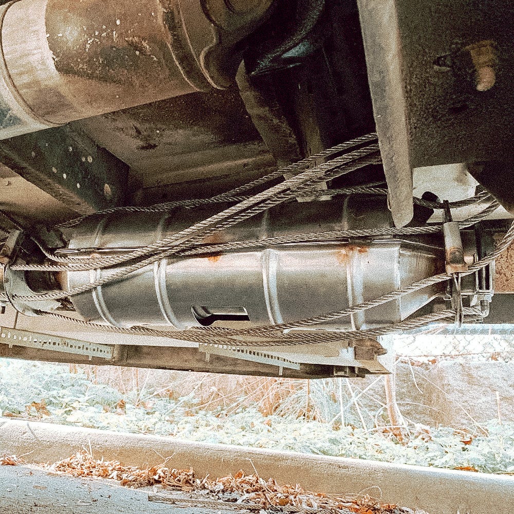 A catalytic converter surrounded by an anti-theft device made of sturdy steel cables.