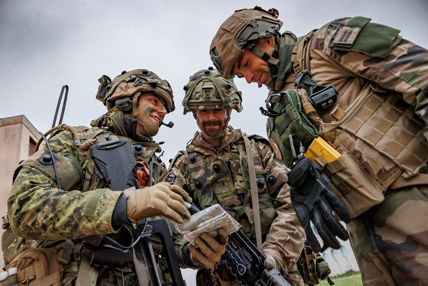 Pipe Major Grant (Centre) converses with two French soldiers before an attack begins during Exercise GAULISH.