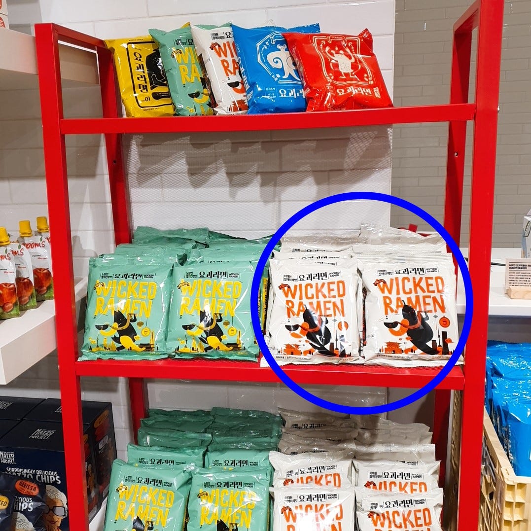 A blue circle pointing out the Wicked Ramen (Yogoe Ramyeon) Itaeweon Chamggae Majemat packages on a shelf.