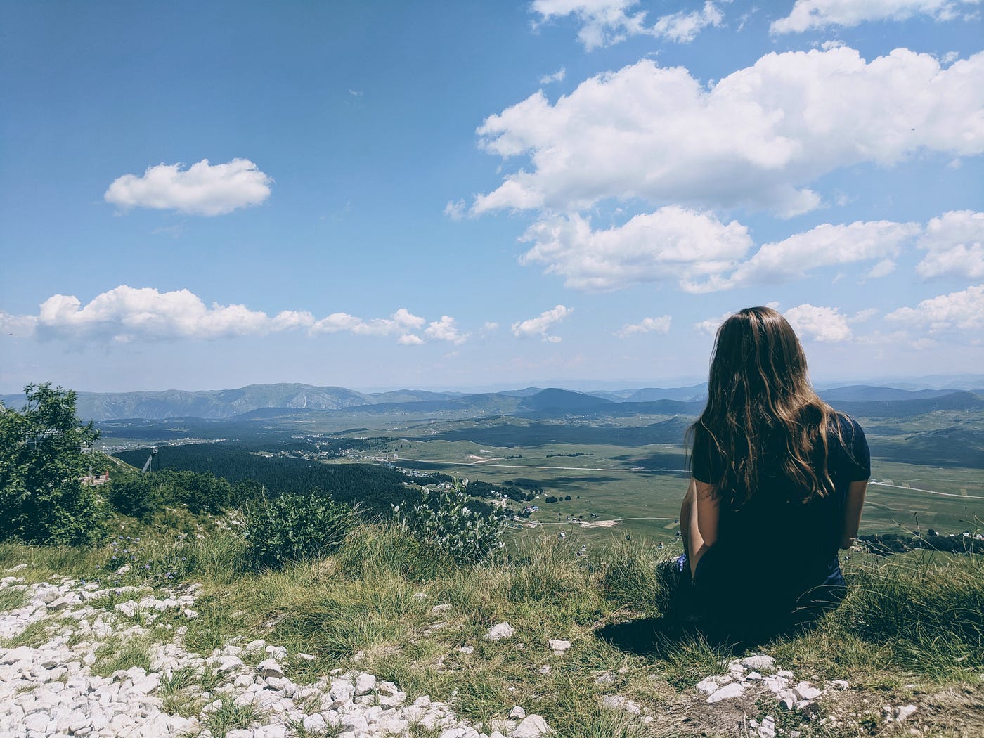 Woman sat on rock all alone looking out into the wilderness