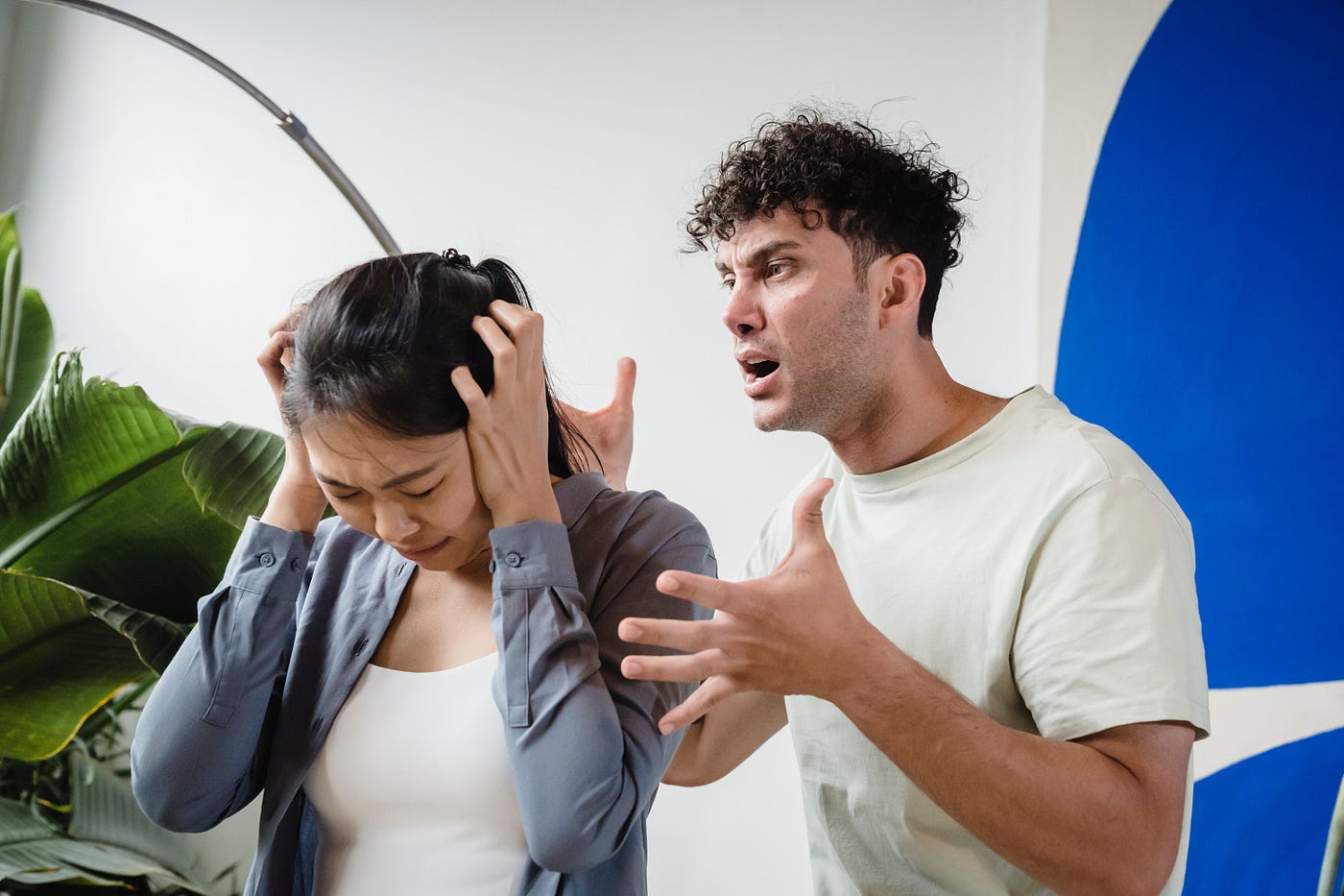 A man talking at a woman with her ears covered.