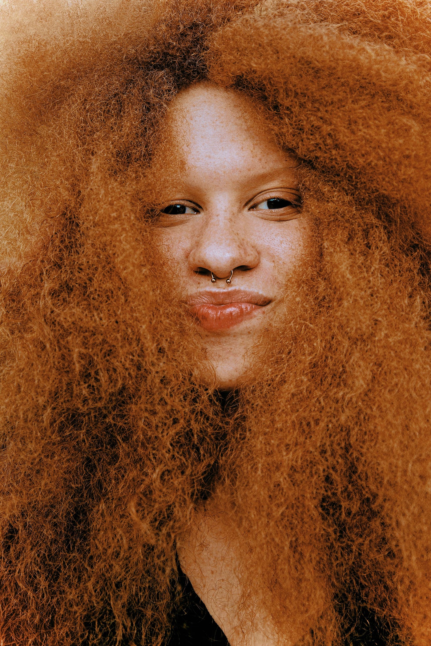 Black woman with big red hair, smiling at camera