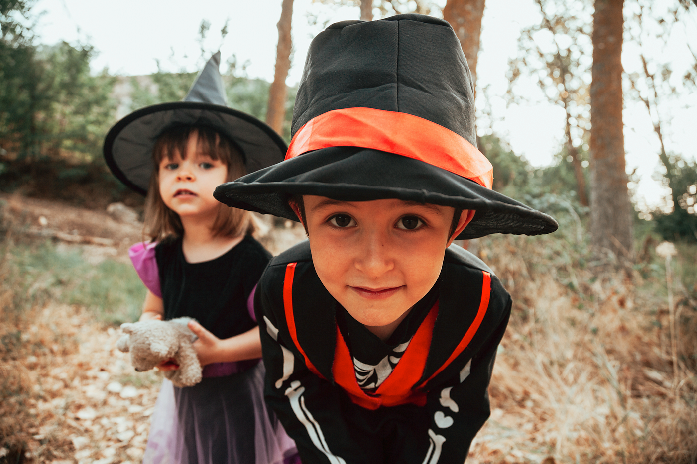 Naturalistic lifestyle photo of two young children dressed up in Halloween costumes trick-or-treating as a witch and a skeleton