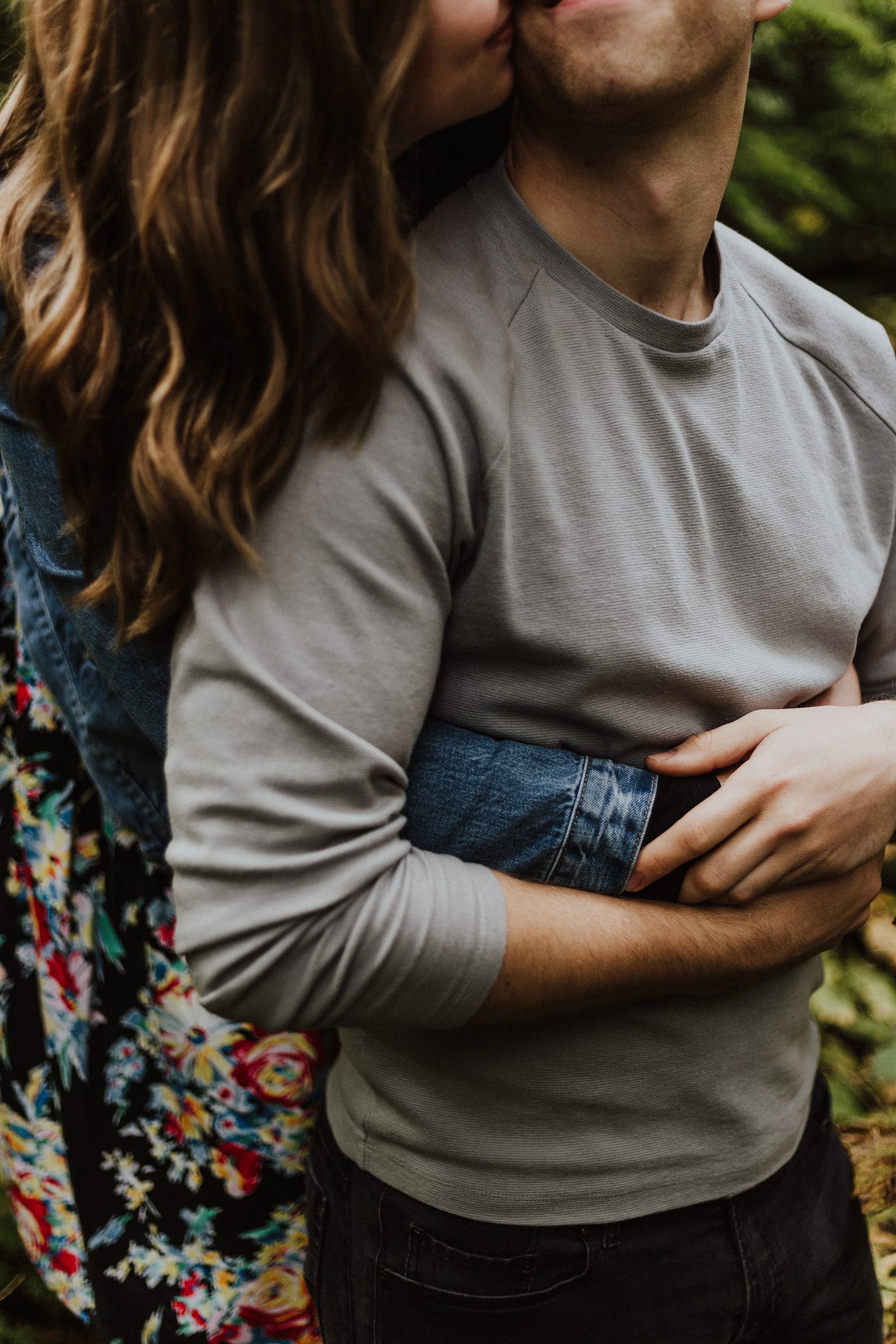 Woman behind Man with her arms around his waist kissing his neck