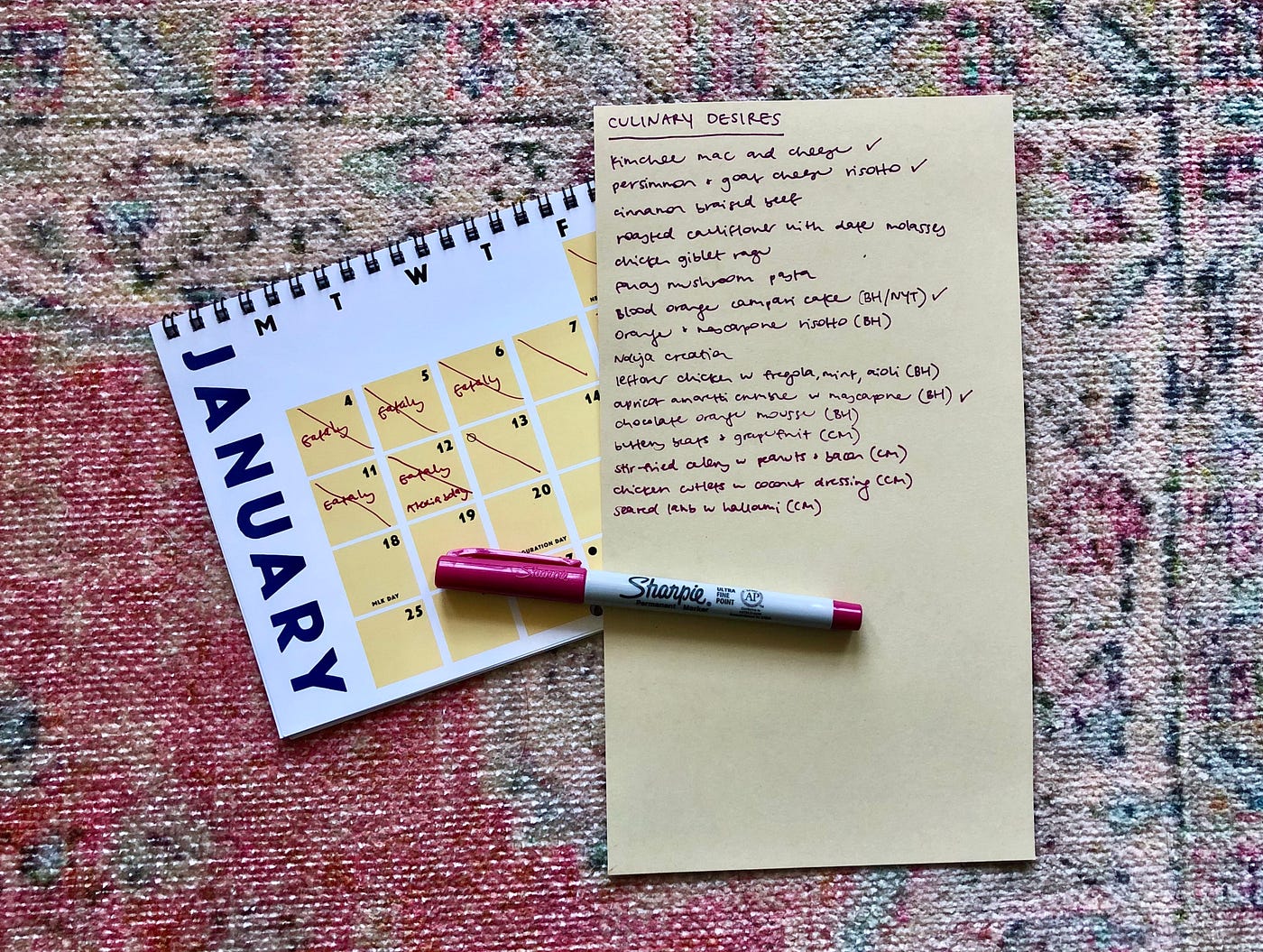 A handwritten list of “Culinary Desires” and a pen on a woven rug next to a calendar turned to the January page.