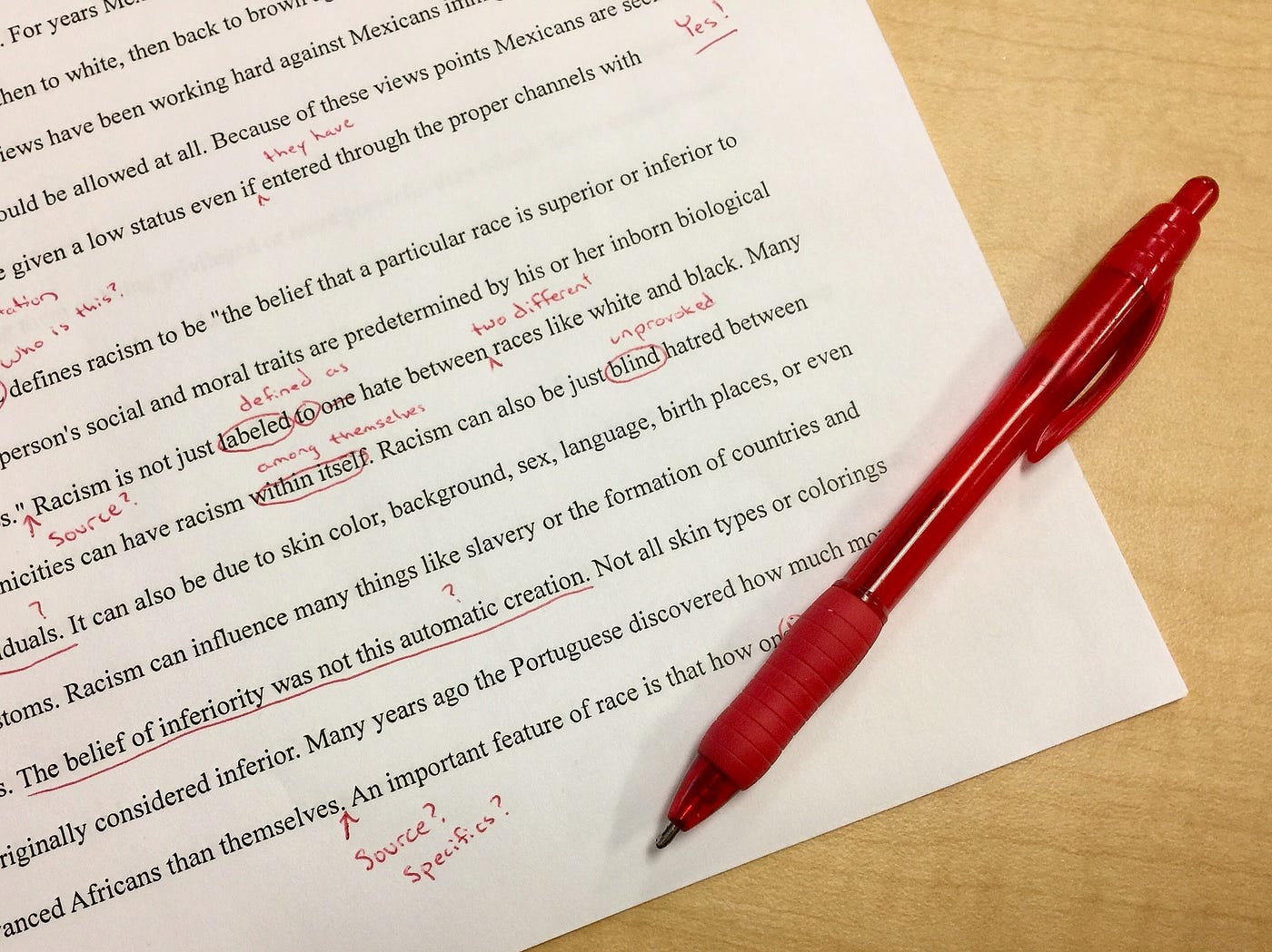 A typed sheet of writing, covered in editor’s marks made in red ink.
