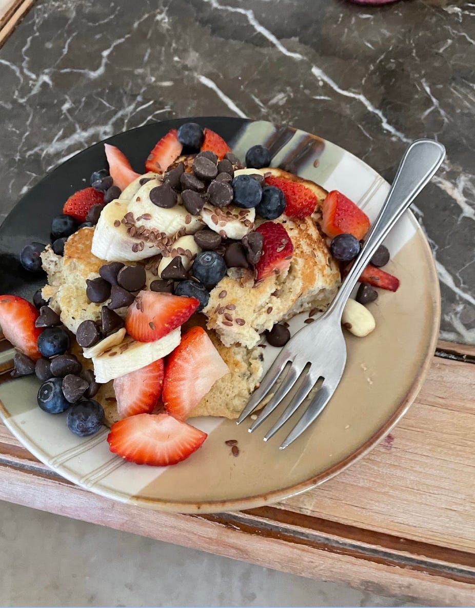 Strawberries, blueberries, nuts, seeds and chocolate chips on top of a pancake.