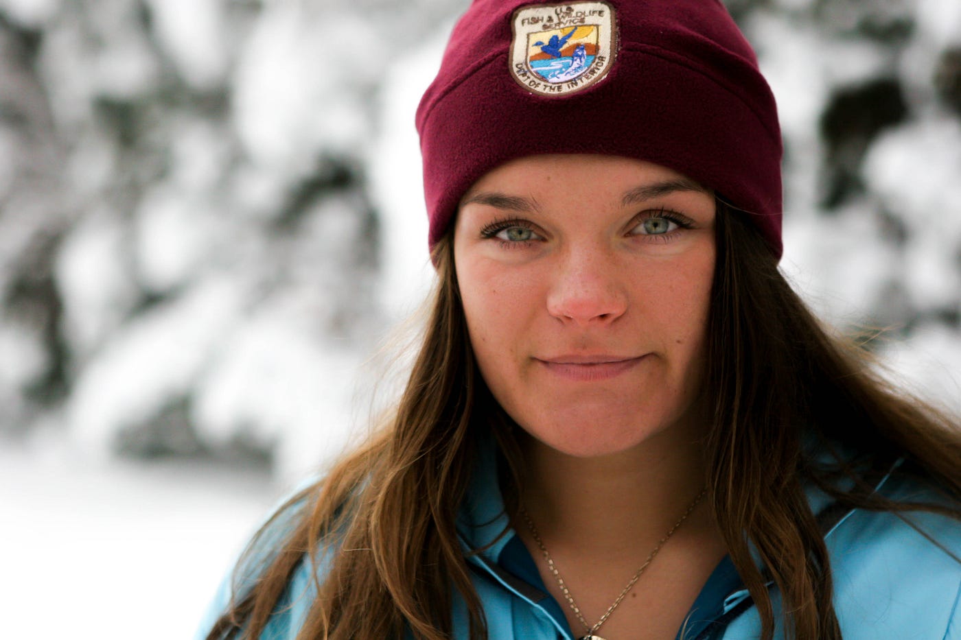young woman in a snowy environment wearing a USFWS hat