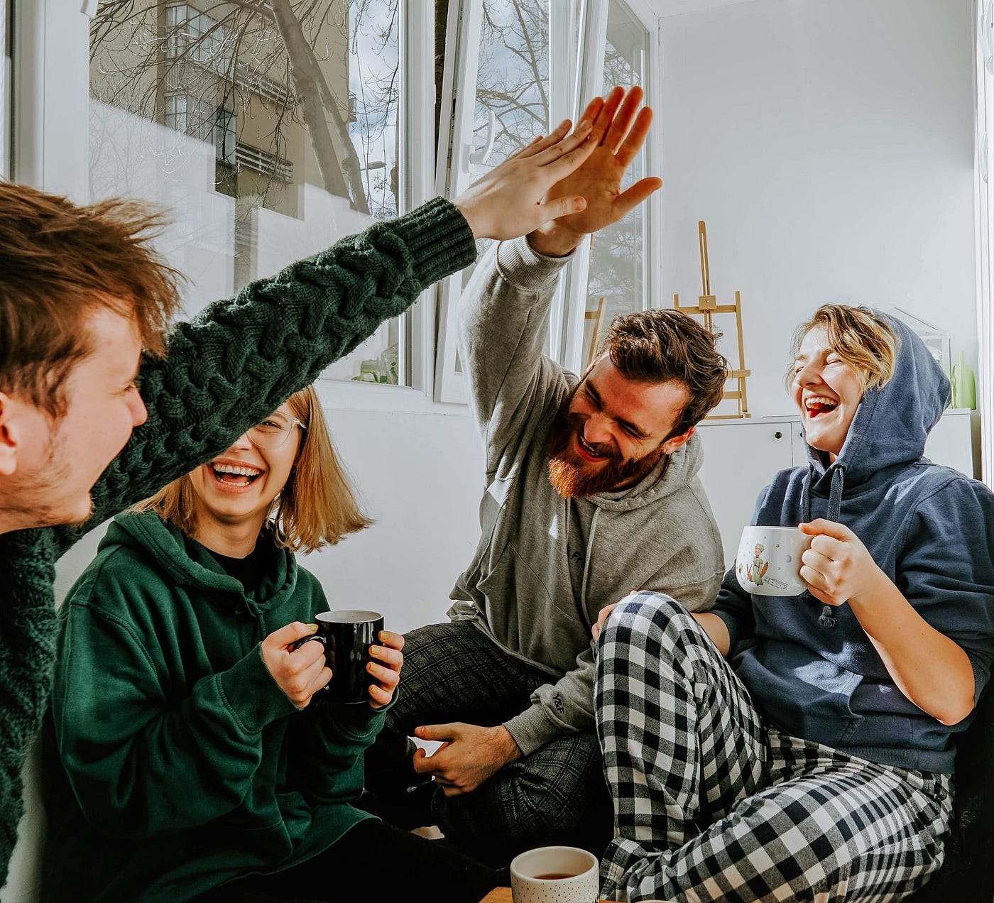 ground of happy friends gathered together drinking tea and doing high fives