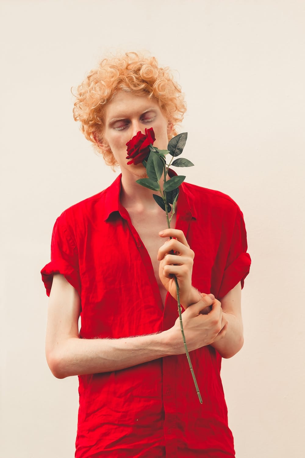 Picture of a skinny guy smelling a rose.