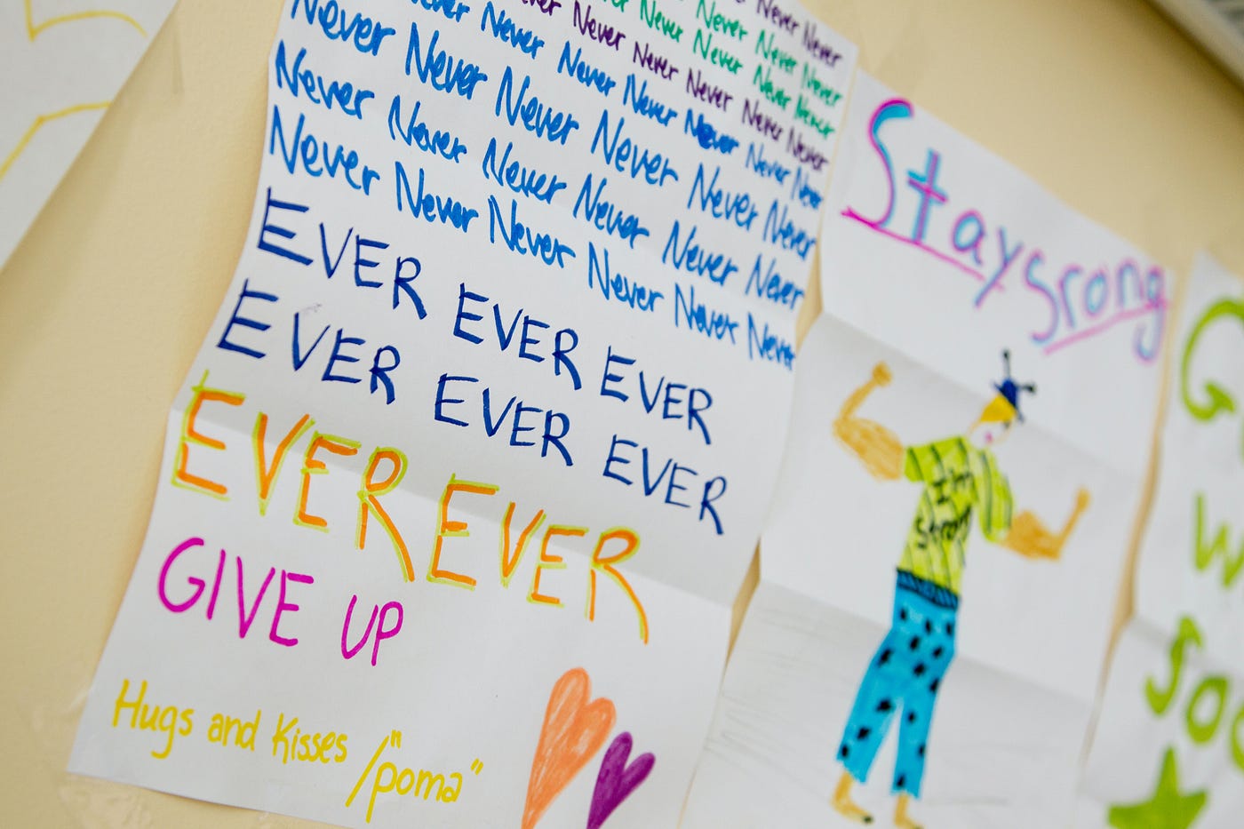 children’s writing that says never ever give up, repeated, and stay strong with a drawing of a strong person