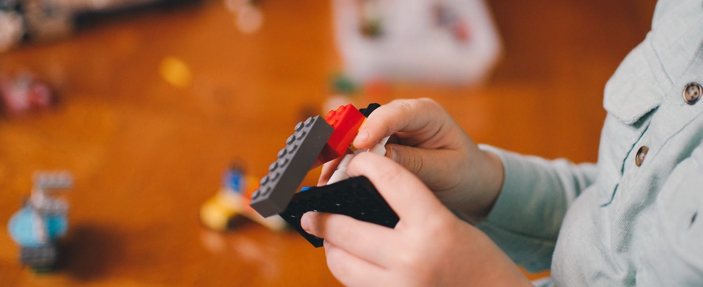 A child's hand holding few lego pieces in hand