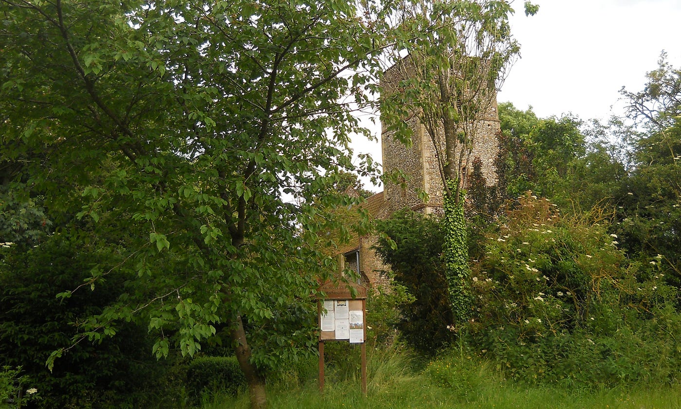 Square tower of a British medieval church hiding behind trees
