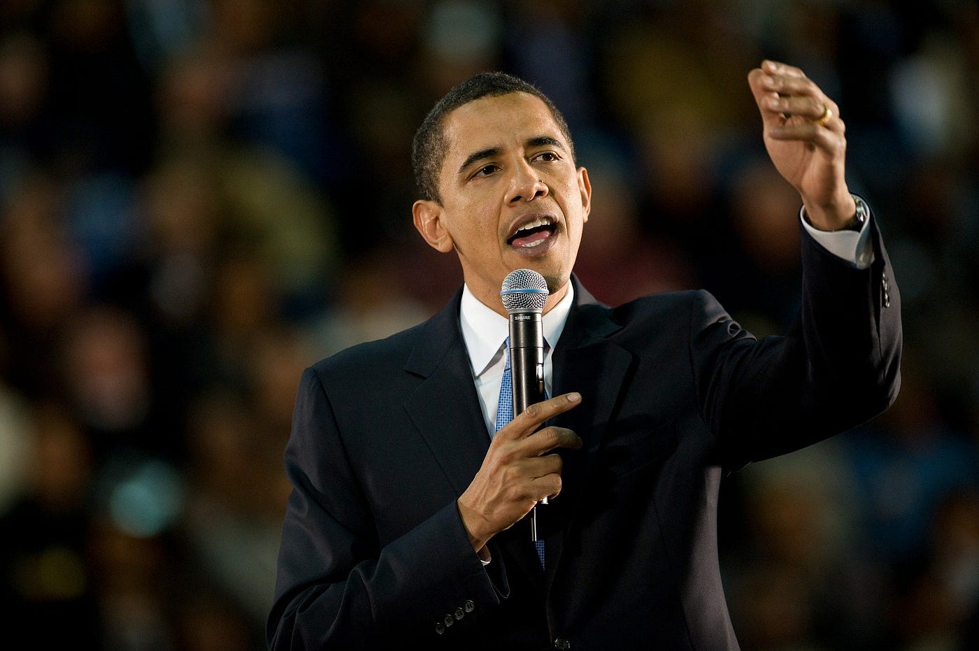 President Obama holds up microphone while delivering remarks to crowd.