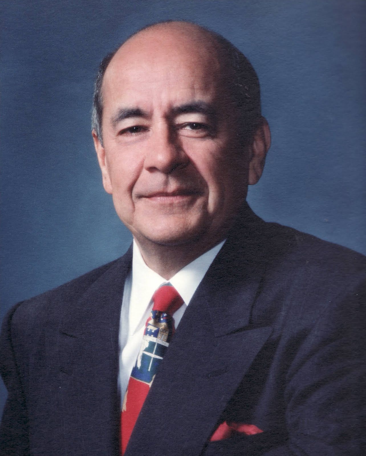 A professional head shot of Fernando Niebla in a suit in front of a blue background