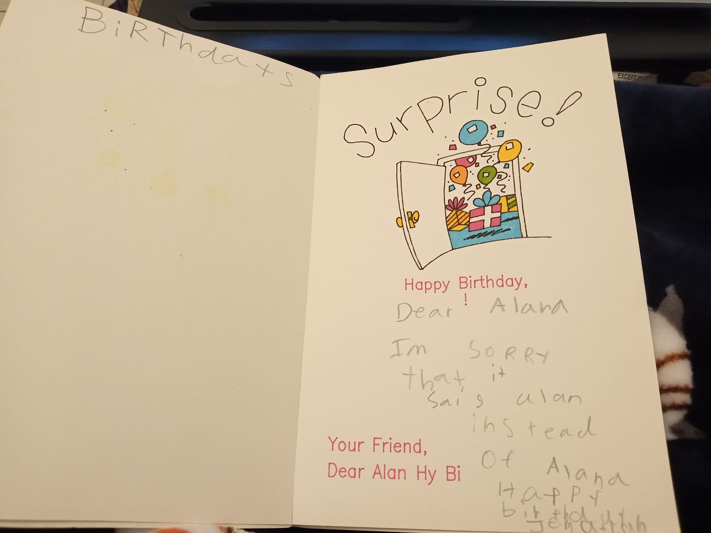 The inside of the birthday card that says “Surprise!” and a picture of balloons coming out of an open door. The writing says “Happy Birthday, Dear Alana Im sorry that it sais alan instead of Alana Happy birthday Jonathan” and on the left of the text is another text “Your Friend, Dear Alan Hy Bi”