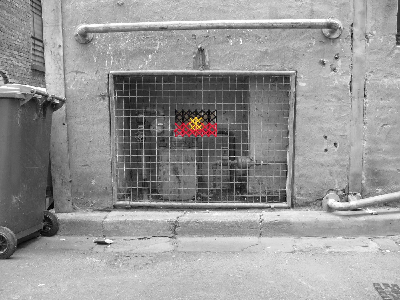 Aboriginal land rights flag cross stitched with yarn onto a steel mesh grid in the laneways of Naarm.