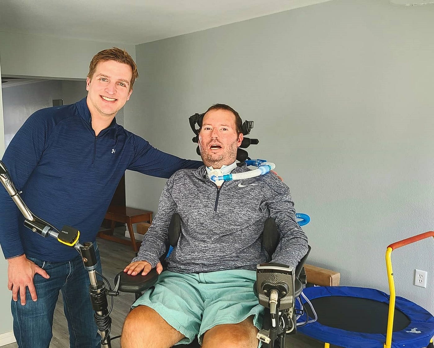 Man standing with another who is in a wheelchair.