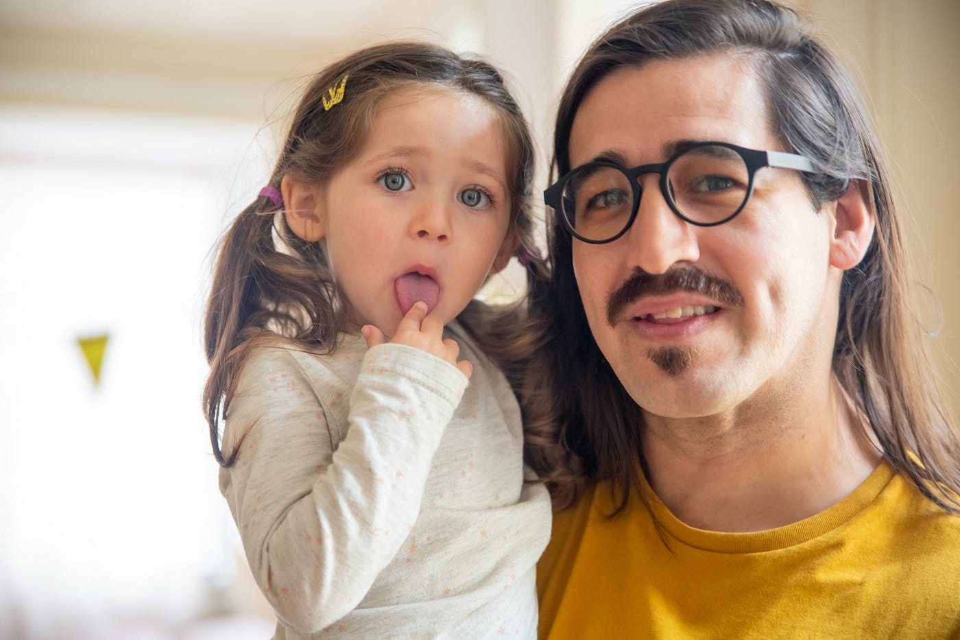 A man with a young child, maybe his daughter. He looks like he’s listening. She has a finger on her tounge. The image represents learning something new about cybercrime and implies cybercrime is relevant to everyday people.