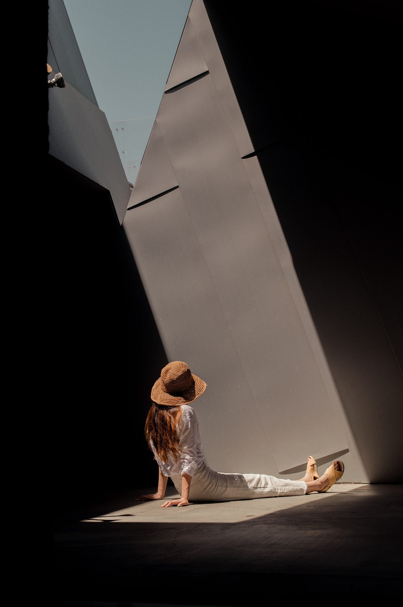 An image of a woman sitting in a building that appears to be post-modern architecture (an angular, dark building).