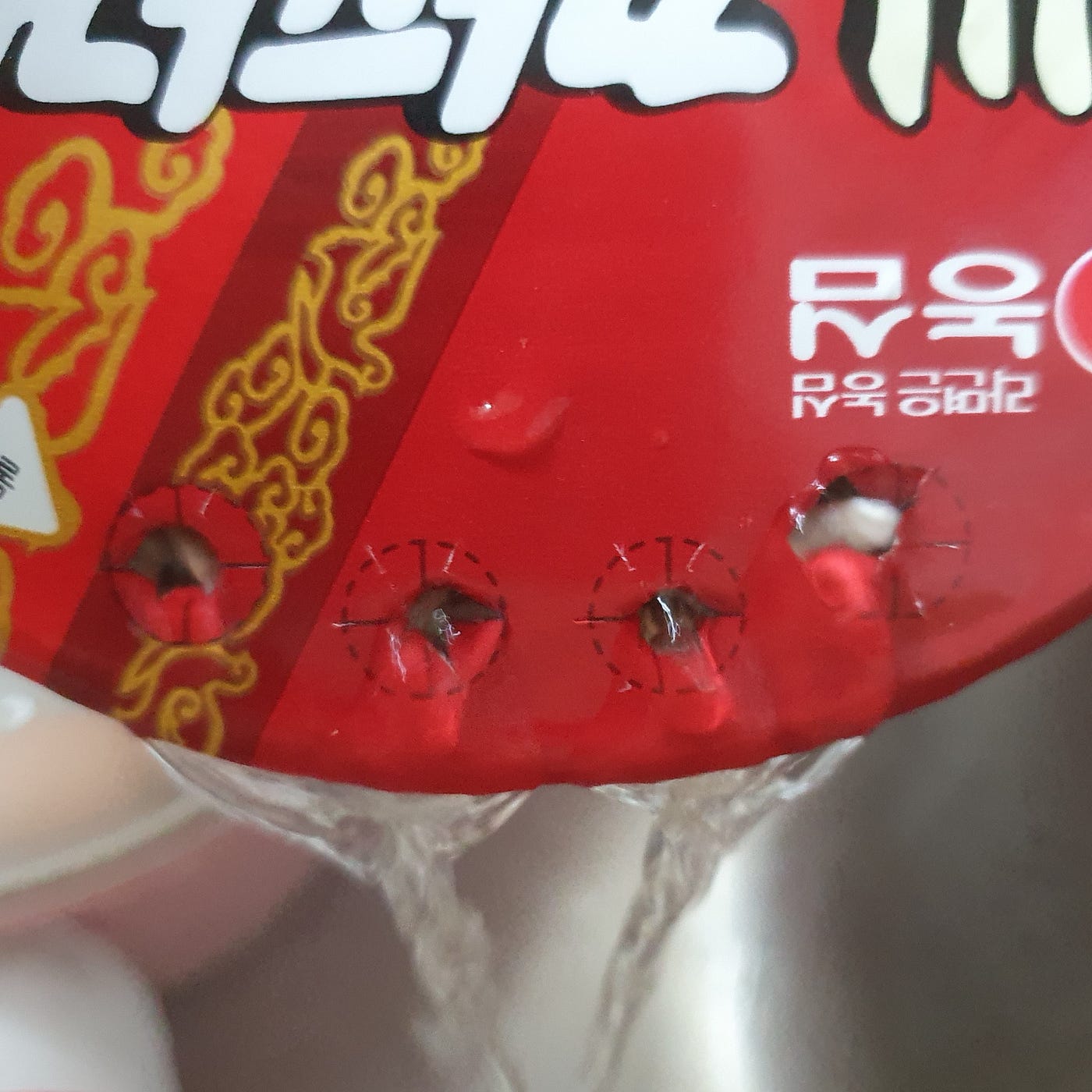 Draining the liquid from a cup of Nongshim Sacheon Chapagetti Instant Noodles.