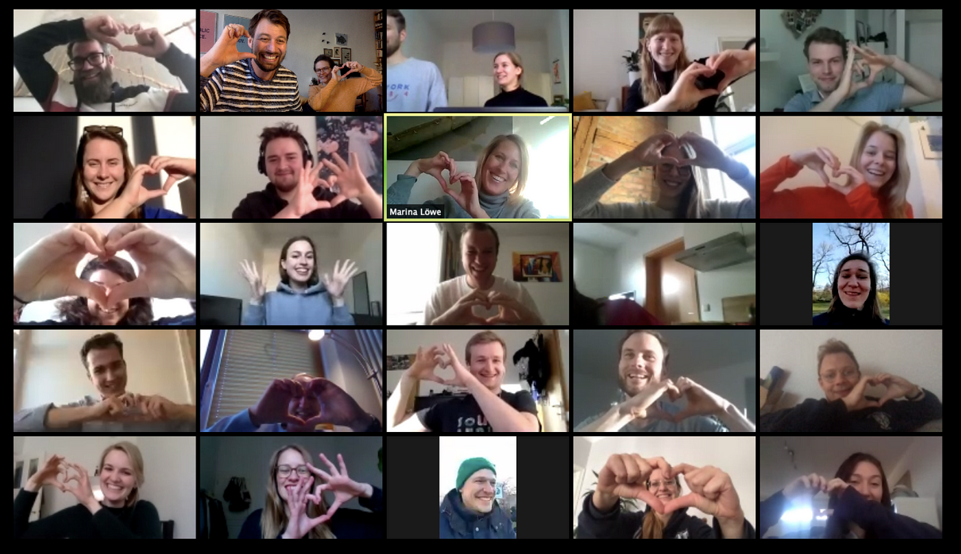 Screenshot of a Zoom meeting showing several participants making the heart symbol with their hands.