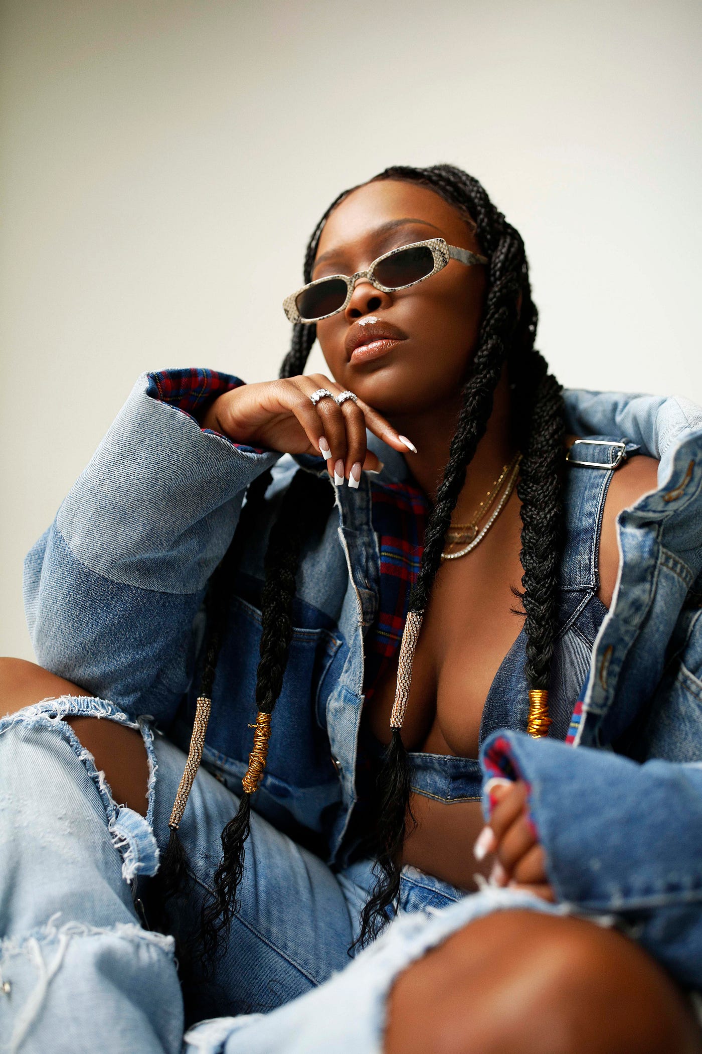 Stylish photo of Charm La’Donna wearing sunglasses and a cool denim outfit, taken from a lower angle.