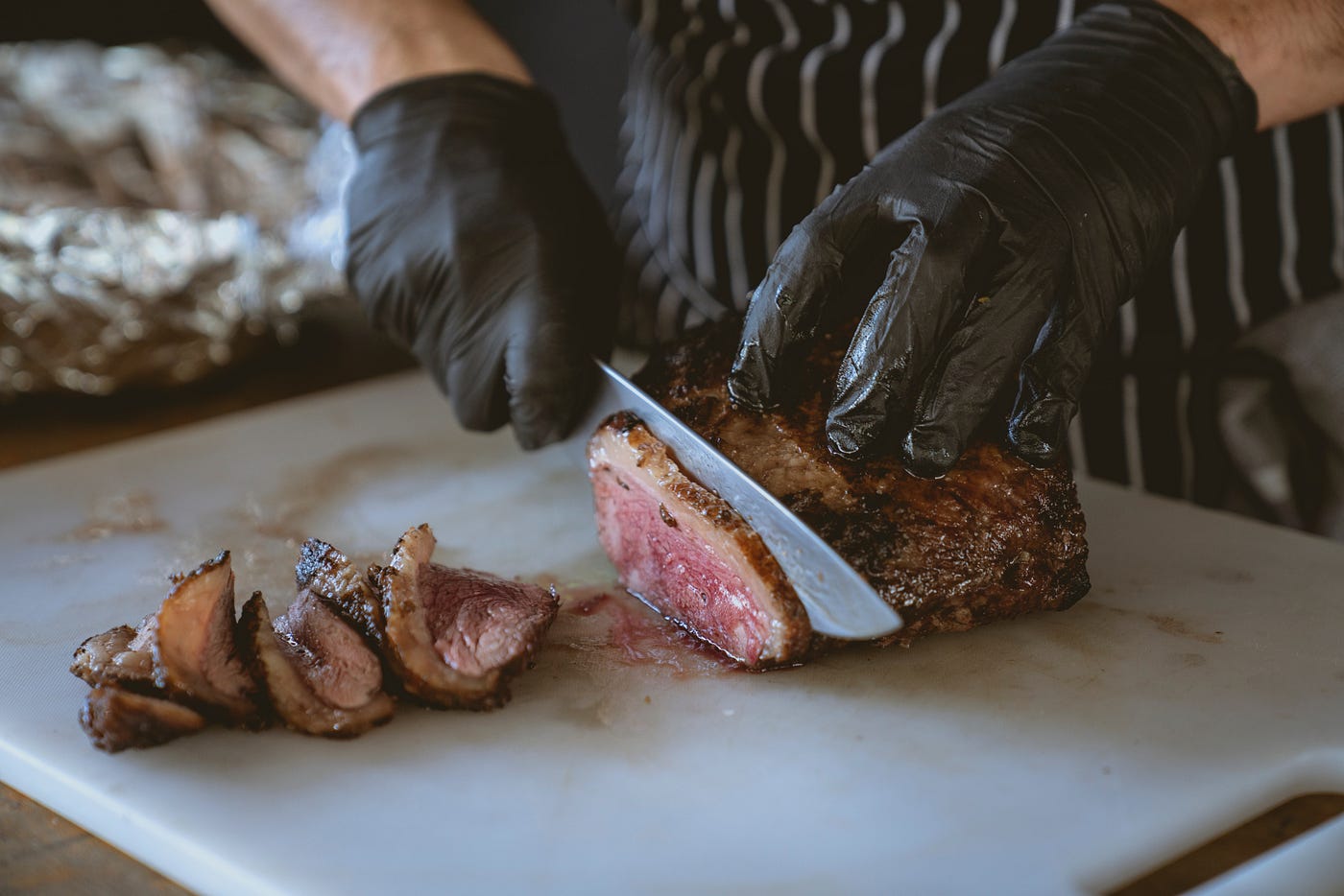A person cutting up a piece of grilled steak.