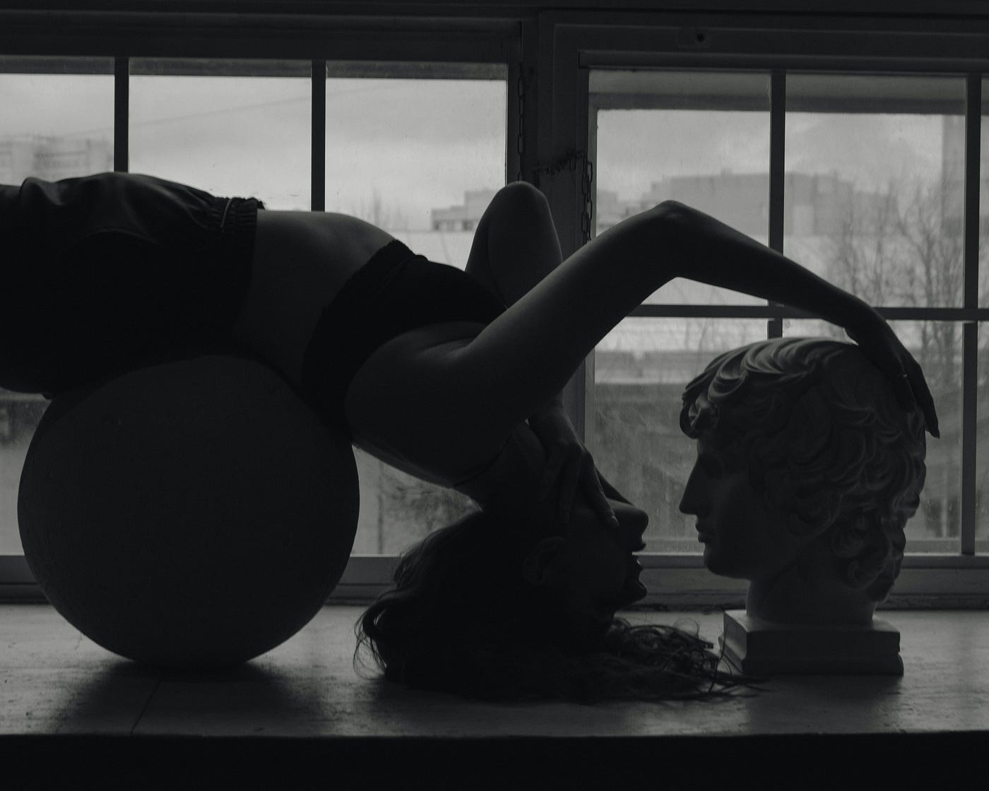 Women laying upside down, facing a statue