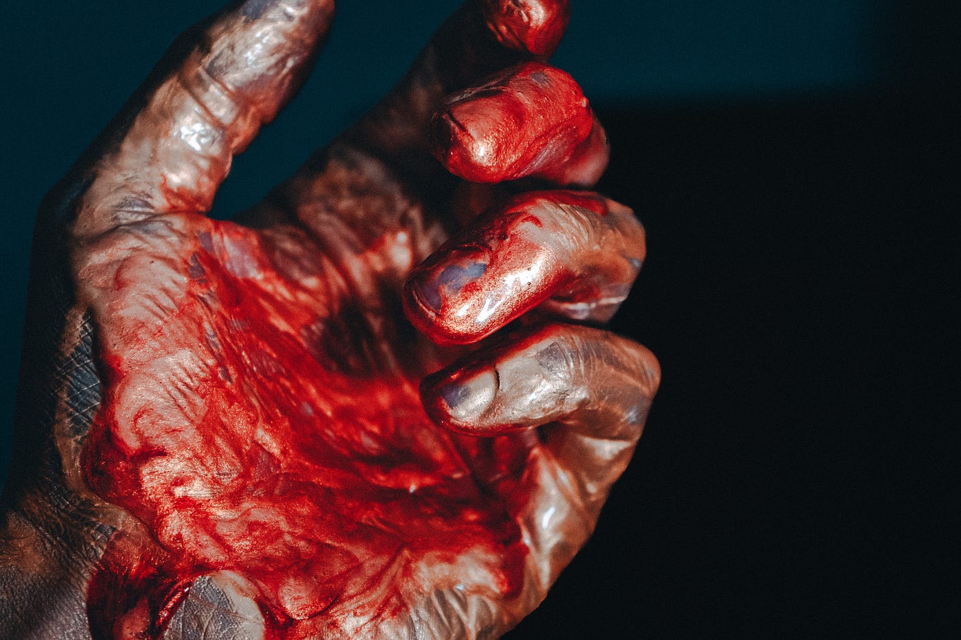 Dirty, blackened masculine hand covered in red paint or blood.