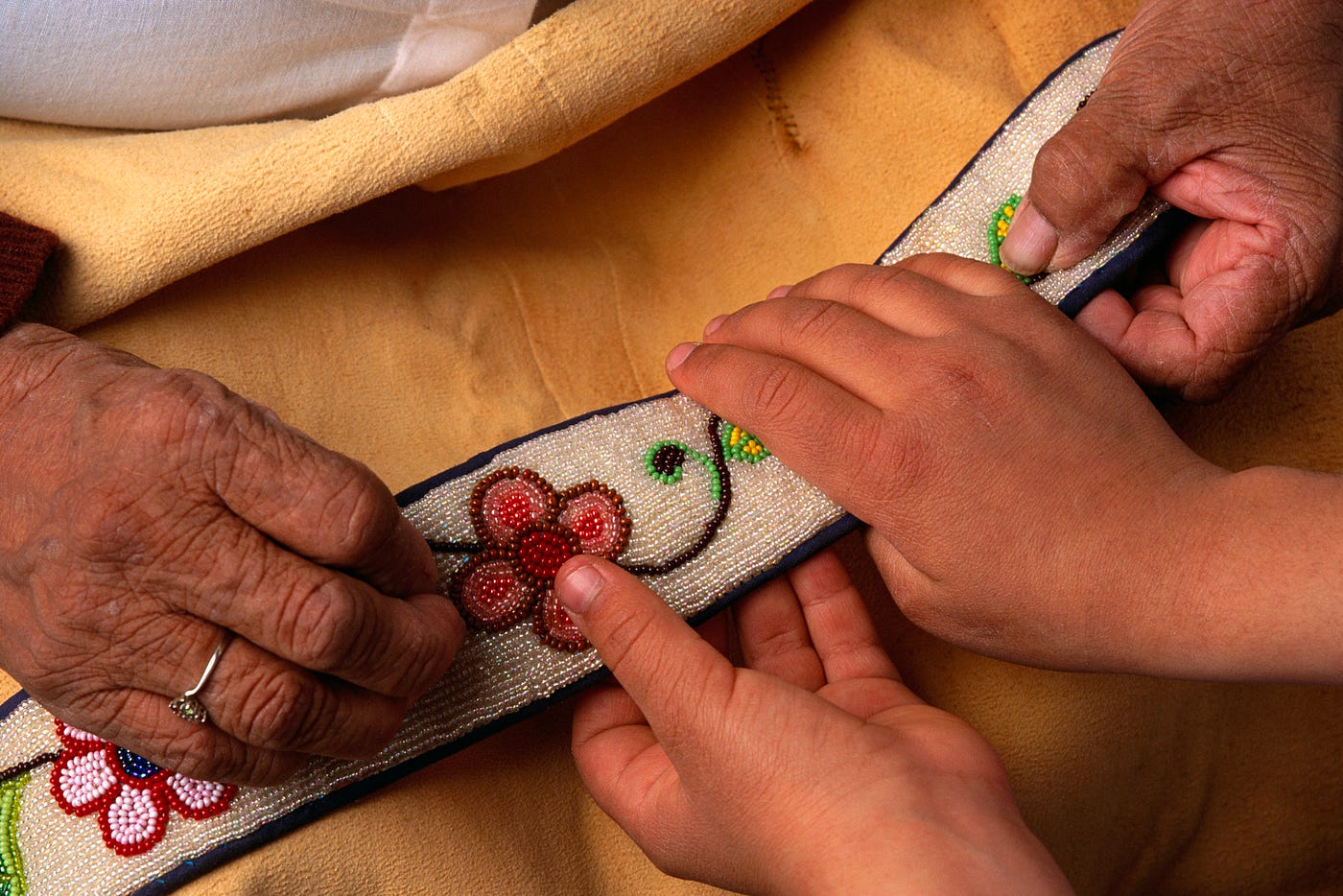 A photo of an elderly Ojibwe showing an embroidery to a young child.
