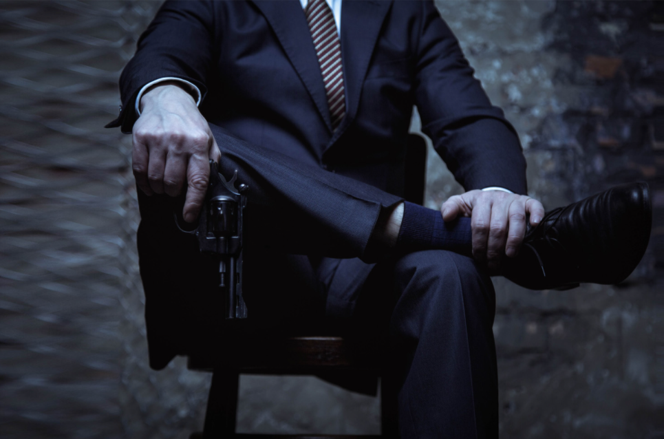 A besuited mafioso holding a revolver.