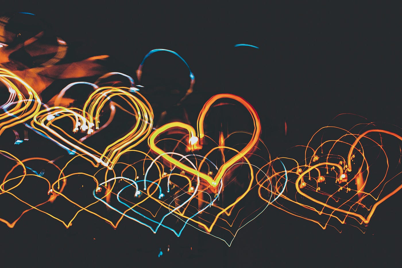 Photo of neon lit hearts in different colors against a black background by Nothing Ahead on Pexels.