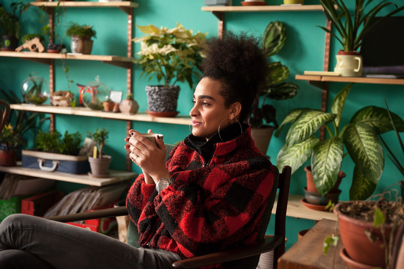 A photo of a woman sitting in a chair in her living room holding a cup of coffee.
