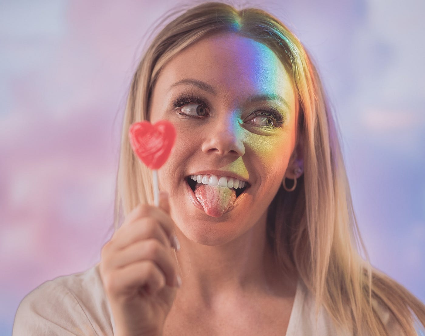 A cheerful lady sticking out her tongue with a love candy in hand