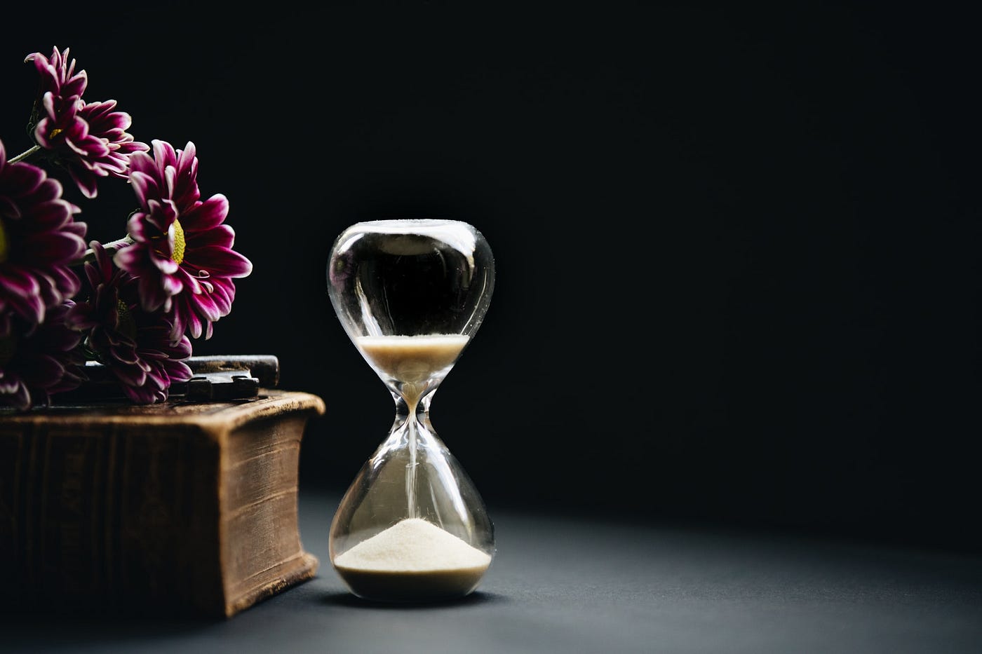 a sand timer placed next to a book with flowers on it
