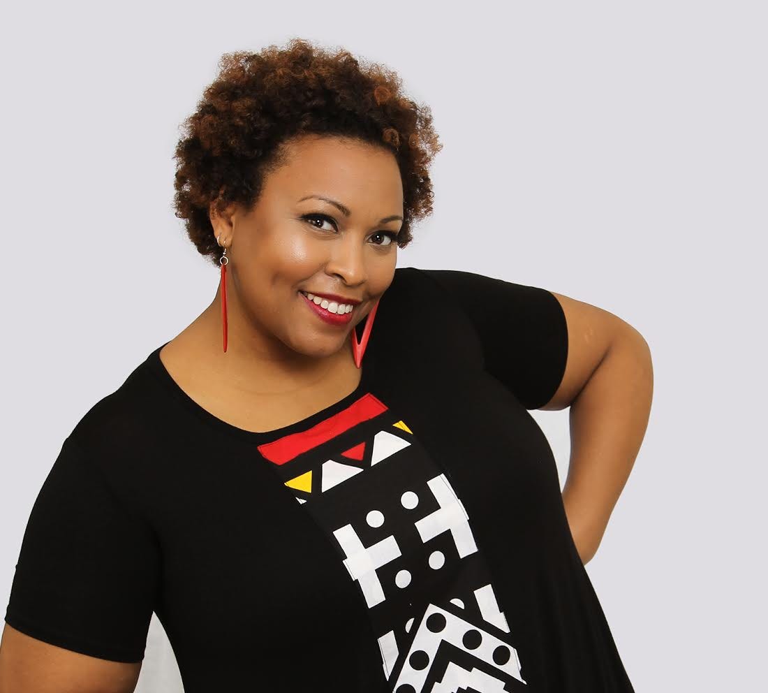 Ella Turenne smiles in front of a white backdrop with her hands on her hips