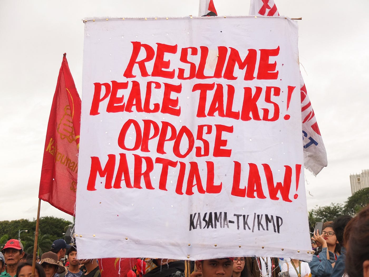 A large banner with a slogan ‘Resume peace talks! Oppose martial law!’ is held aloft during a demonstration.