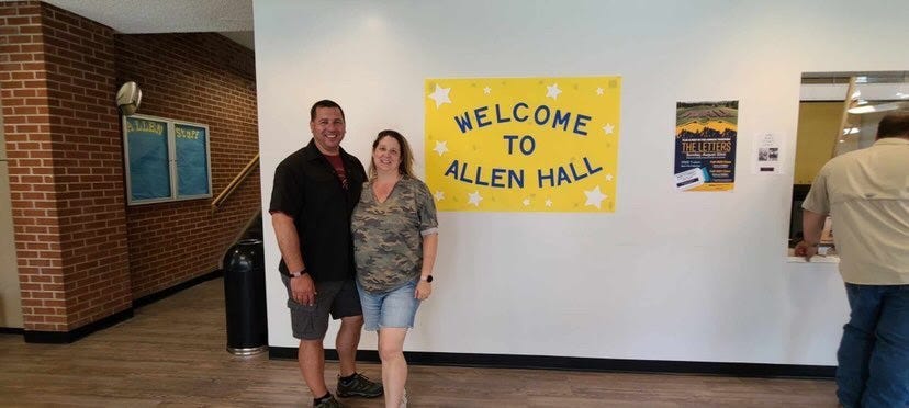 couple in front of “welcome to Allen Hall” sign