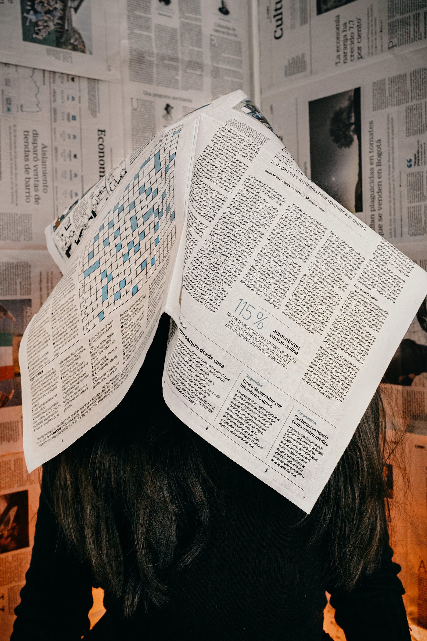 A person with a newspaper on her head.