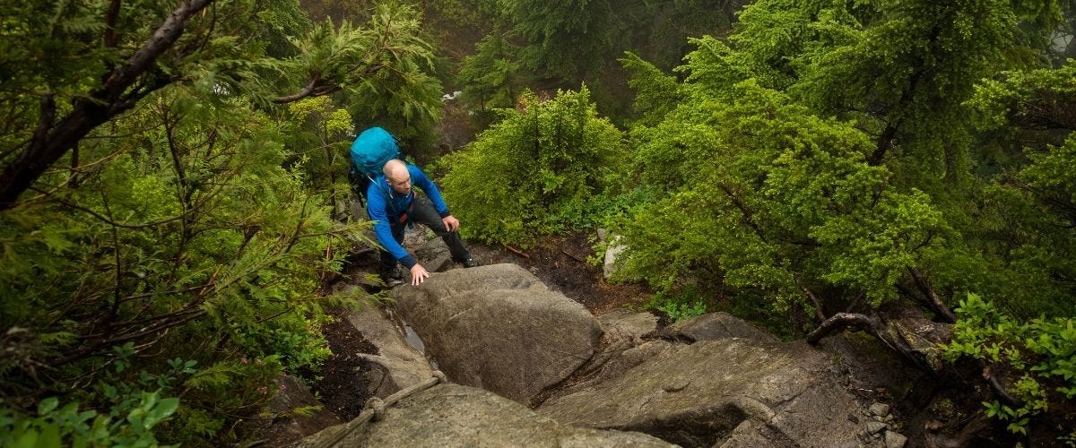 a man backpacking up a rock-strewn hill