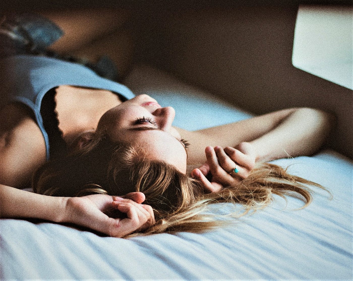 woman with brown hair laying on her back in bed