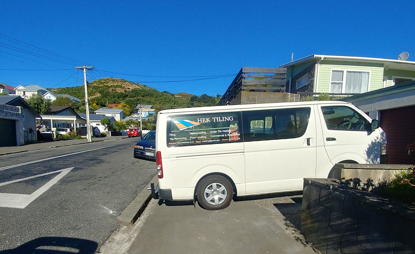 A white van parks completely across a footpath.